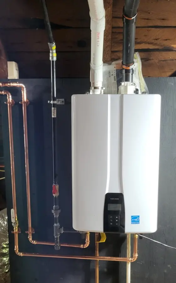 A Navien tankless water heater on a dark backer board, with its copper supply loops